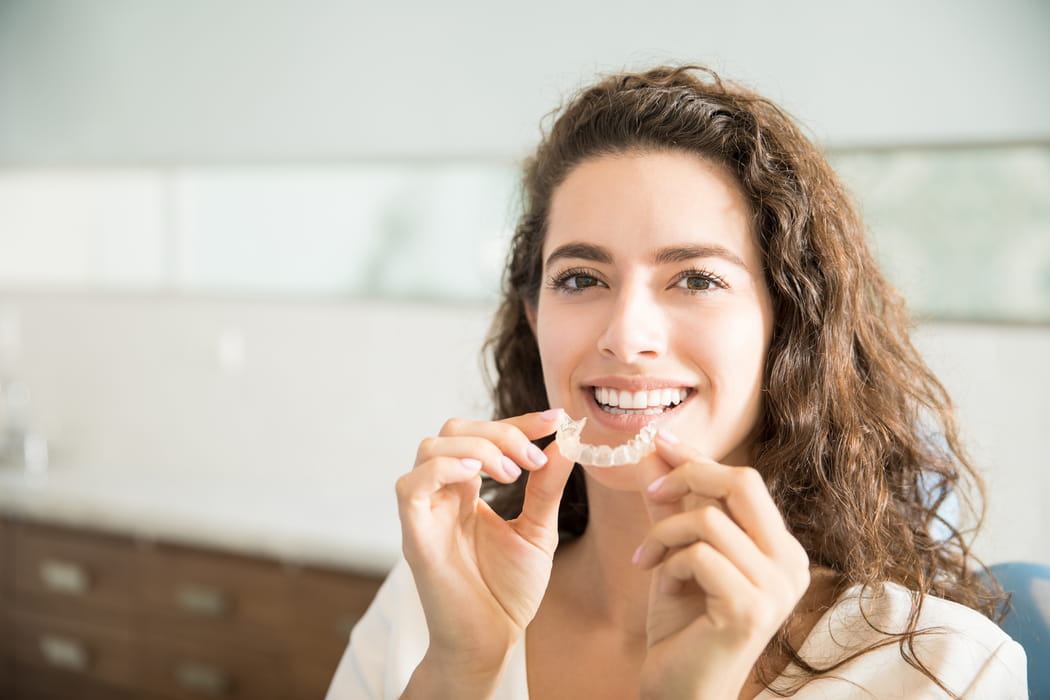 Pacjentka trzymająca przezroczystą nakładkę ortodontyczną Invisalign